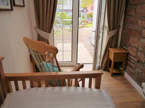 Ein Zimmer mit einem hölzernen Bett, einem Sessel, einem kleinen Holztisch und einer Schiebetür zu einer Außenpatio.