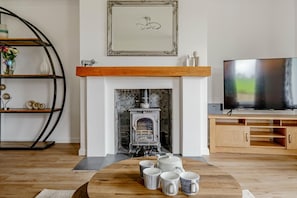 A living room with a fireplace, a television, and a coffee table with mugs. - 3 Bed in Dumfries (oc-d641667) (Torthorwald)