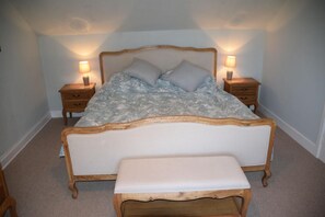 Ein Schlafzimmer mit einem hölzernen Bett, zwei Nachttischen und einer Bank.
