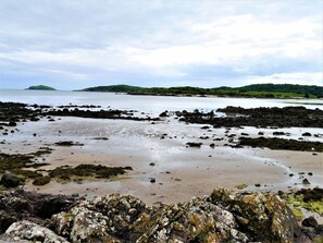 A rocky shoreline with a view of distant green hills and a body of water. - 4 Bed in Rockcliffe (oc-d585839) (Rockcliffe)