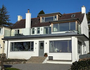 Ein zweistöckiges Haus mit flachem Dach, großen Fenstern und einer gemauerten Steinbasis.