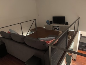 A modern living room with a sofa, a flat-screen TV, and a staircase. - Experience Genoa: A Charming Apartment in the Heart of Its Historic Center (Genova)