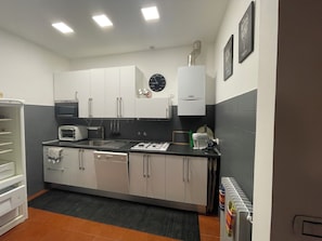 A modern kitchen with white cabinets, a built-in oven, a microwave, and a sink. - Experience Genoa: A Charming Apartment in the Heart of Its Historic Center (Genova)