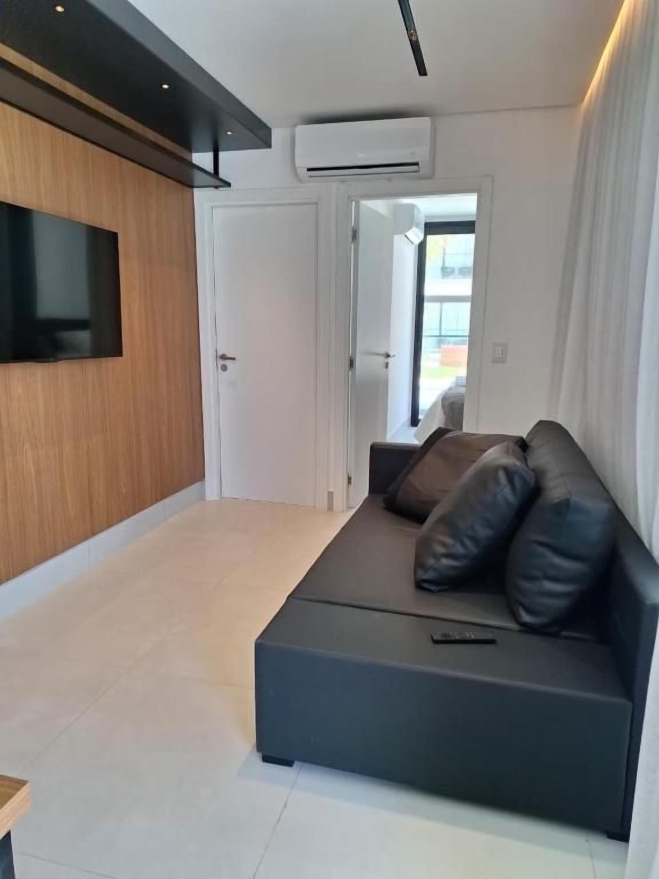 Un salon moderne avec un canapé, un téléviseur à écran plat fixé au mur et un appareil de climatisation.