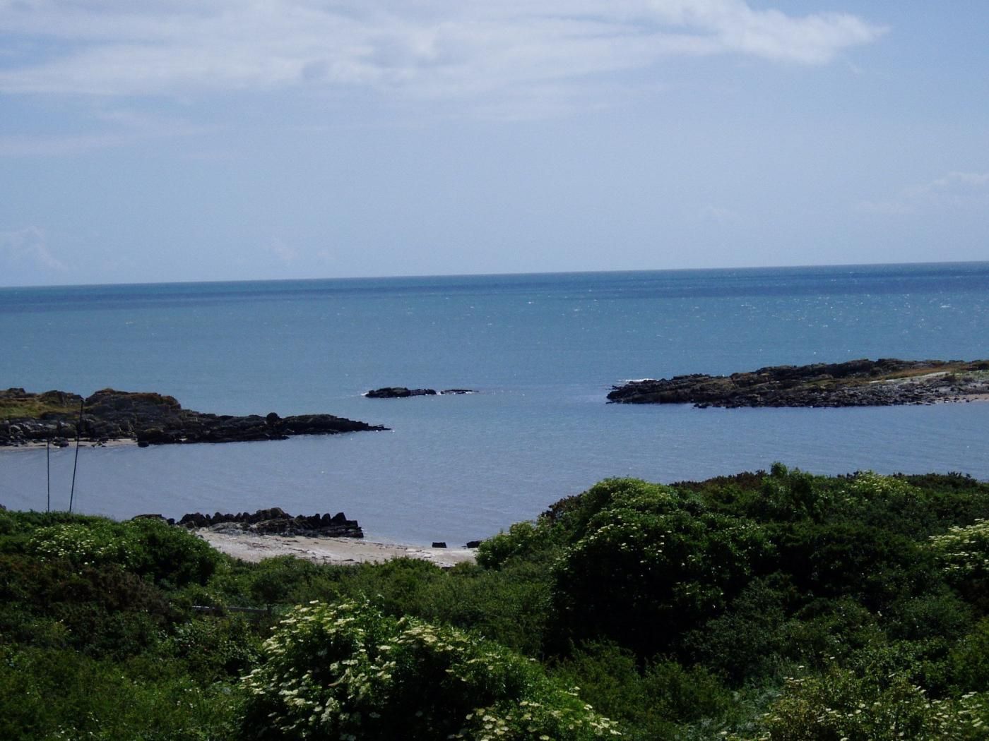 A coastal landscape with rocky outcrops and a beach.