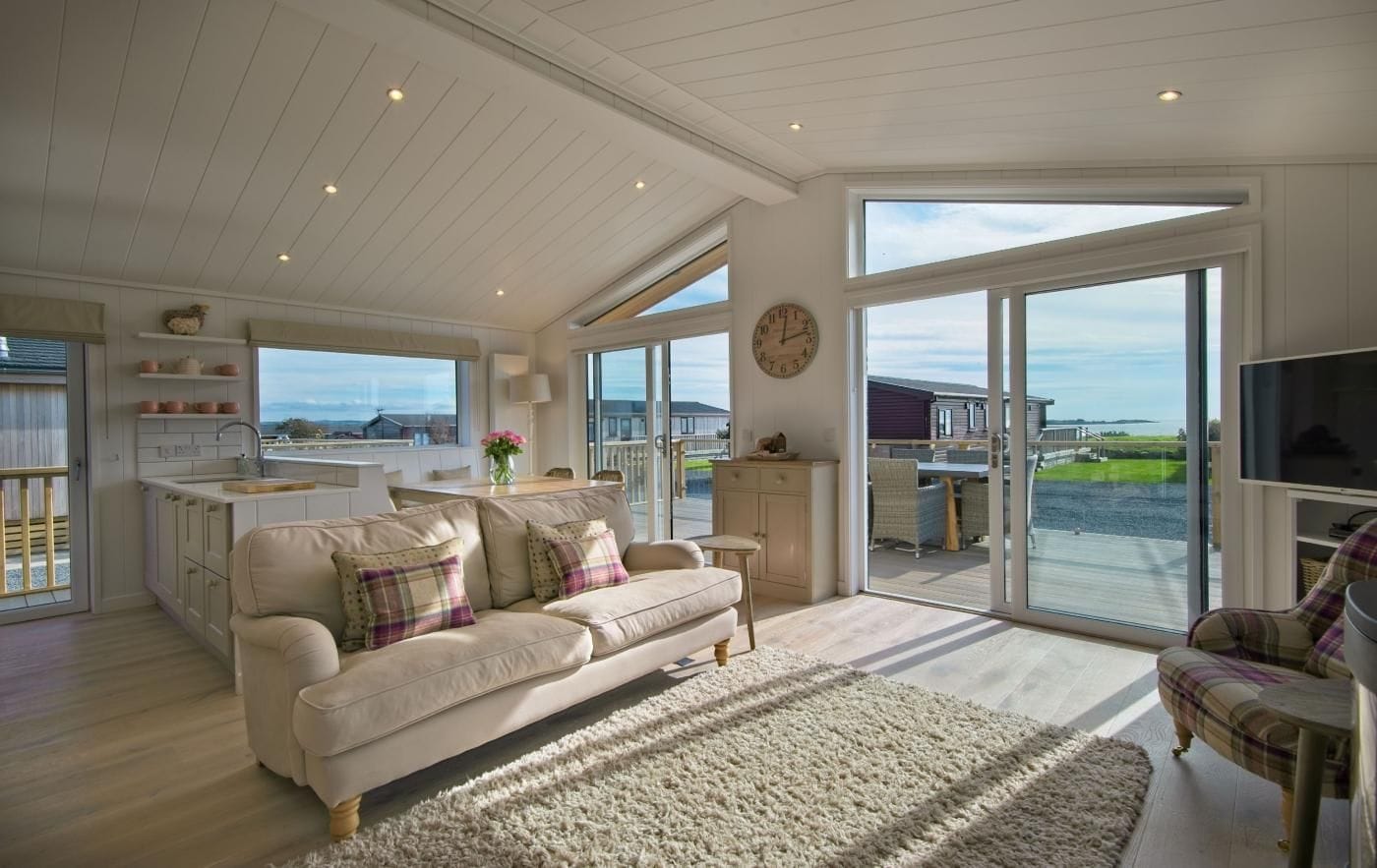 Un salón amplio con un sofá grande, televisor y vistas al exterior.