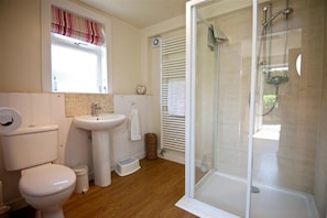 Une salle de bain équipée de toilettes, d’un lavabo et d’une douche à parois de verre.
