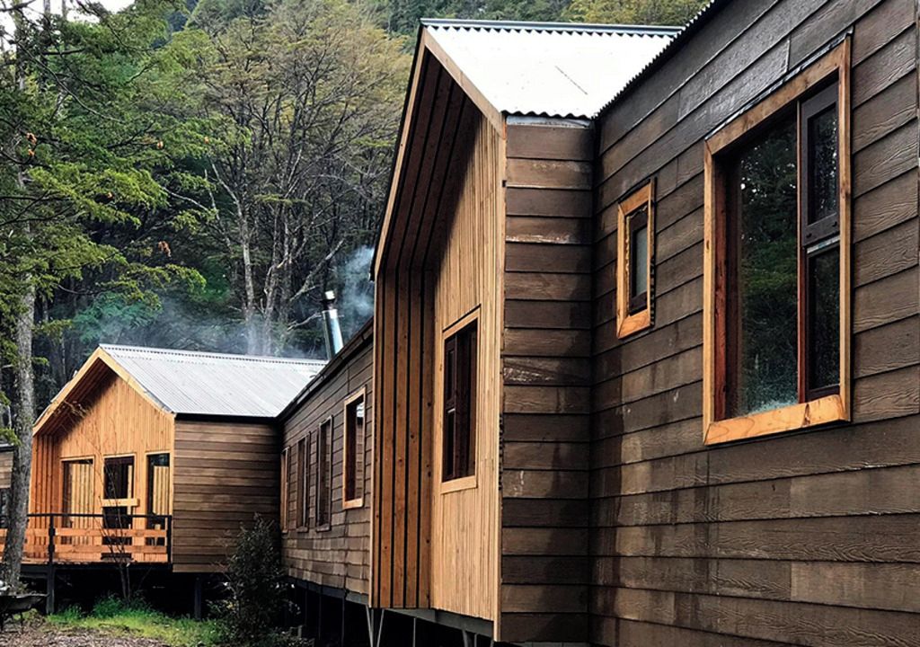 Une rangée de cabanes en bois, dotées d’un toit à pente, entourées d’arbres.