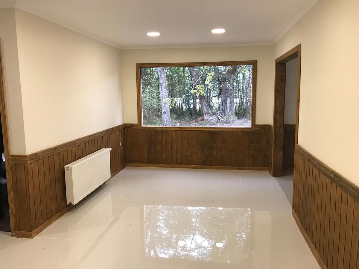 A room with a large window, wooden paneling, and a radiator.