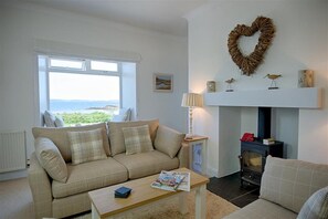 A living room with a sofa, a coffee table, a fireplace, and a view of the outdoors.