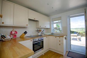 A kitchen with white cabinets, a wooden countertop, a built-in oven, and a window with a view of the outdoors.