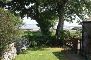 A stone wall, a wooden gate, and a grassy area leading to a beach.