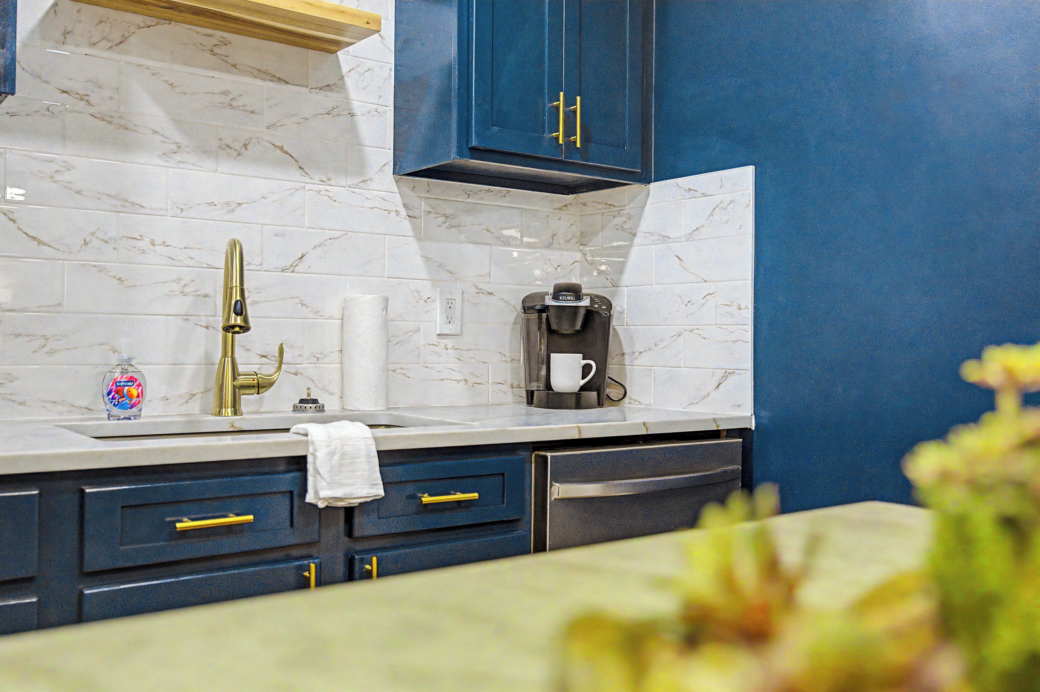 A kitchen with marble tiles, a coffee maker, and blue cabinets.