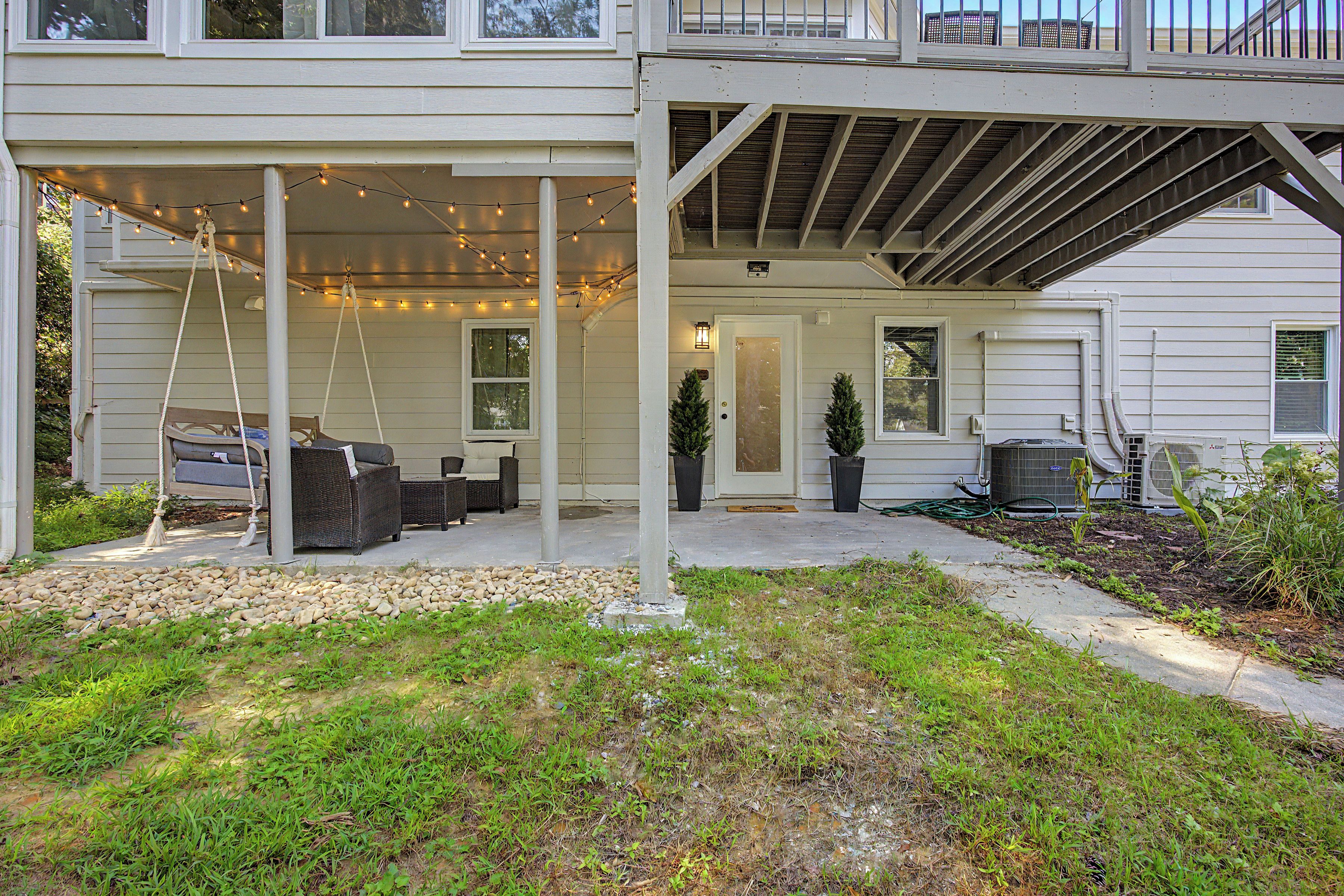 A covered porch with outdoor furniture, string lights, and a door leading to the house.