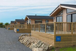 A row of wooden cabins with glass railings, labeled 'Clover Lodge.' - 3 Bed in Mossyard, Gatehouse Of Fleet (oc-d555706) (Gatehouse of Fleet)