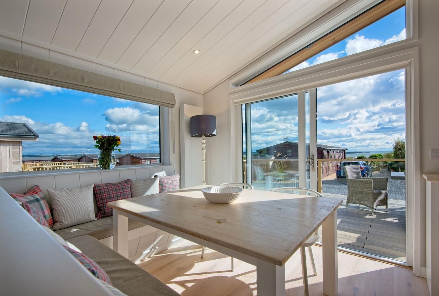 Un balcón amplio con una mesa y sillas de madera, con vistas panorámicas al mar y edificios.