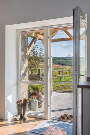Ein Zimmer mit einer großen Glasdoor, die zu einem Außenbereich mit Blick auf ein Weinberg führt.