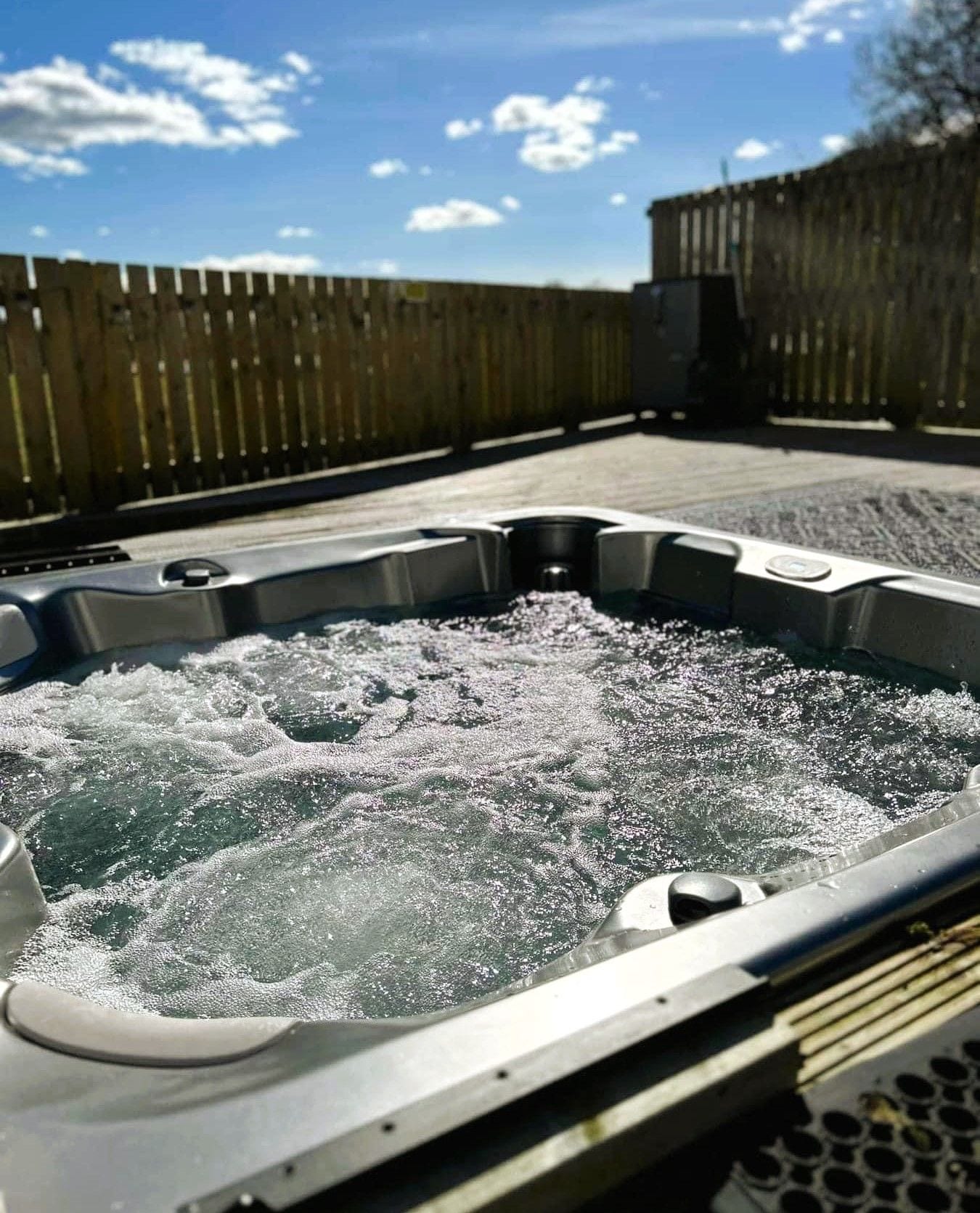 A hot tub with a wooden fence in the background.
