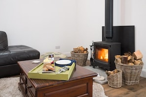 Una sala de estar acogedora con chimenea, una mesa de comedor con comida y un sofá cómodo.