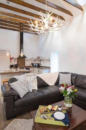 Una sala de estar moderna con un sofá de cuero oscuro, una mesa de centro de madera con una bandeja de comida y un candelabro original.
