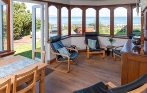Ein Eckzimmer mit Meerblick, Holzmöbel und einem Esstisch.