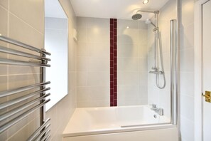 Ein modernes Badezimmer mit einer gläsernen Duschkabine, einer weißen Badewanne und einem Handtuchhalter.