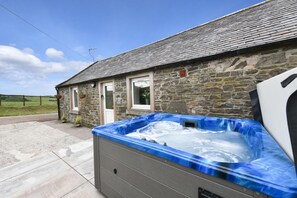 Ein Steinhaus mit Whirlpool davor.