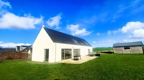 A modern white building with a sloped roof, a patio area, and a grassy yard. - 4 Bed in Castle Douglas (oc-d637110) (Rhonehouse)