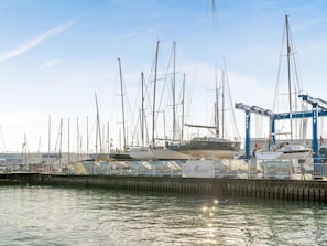 Ein Yachthafen mit mehreren Segelbooten, einem Kran und einem Gebäude mit Beschilderung.