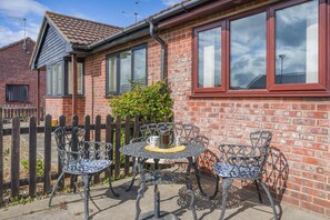 A brick house with a tiled roof, a fenced yard, and a patio with a table and chairs. - 2 Bed in Walcott (oc-c46378) (Walcott)
