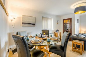 A dining area with a glass table, black leather chairs, and a wooden side table with a lamp. - 2 Bed in Walcott (oc-c46378) (Walcott)