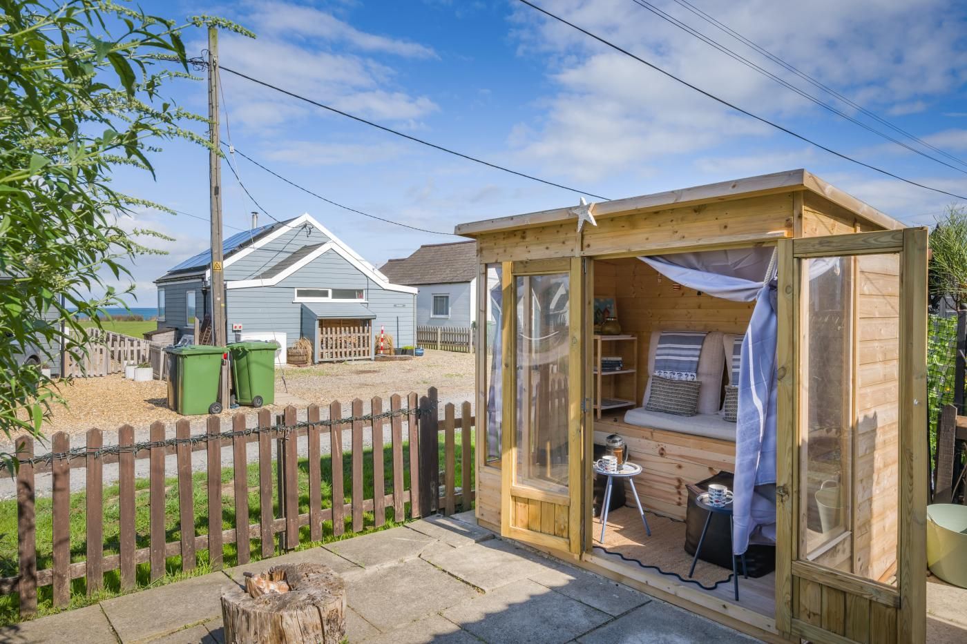 A wooden cabin with a glass door, a small table, and a bench.