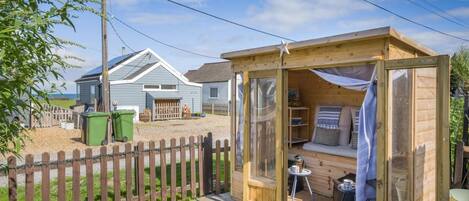 A wooden cabin with a glass door, a small table, and a bench.