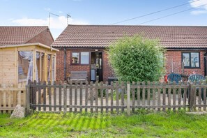 A brick house with a tiled roof, a wooden fence, and a garden area. - 2 Bed in Walcott (oc-c46378) (Walcott)