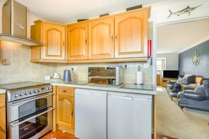 Eine kleine Küche mit Holzausstattung, einem Backofen und einem Geschirrspüler.