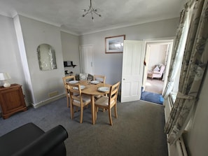 A dining area with a round table set for four, wooden chairs, a small cabinet, and a mirror on the wall. - 2 Bed in Overstrand (oc-s46412) (Overstrand)
