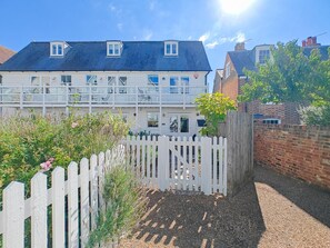 Ein Wohnhaus mit weißem Zaun, Kiesweg und Backsteinmauer.