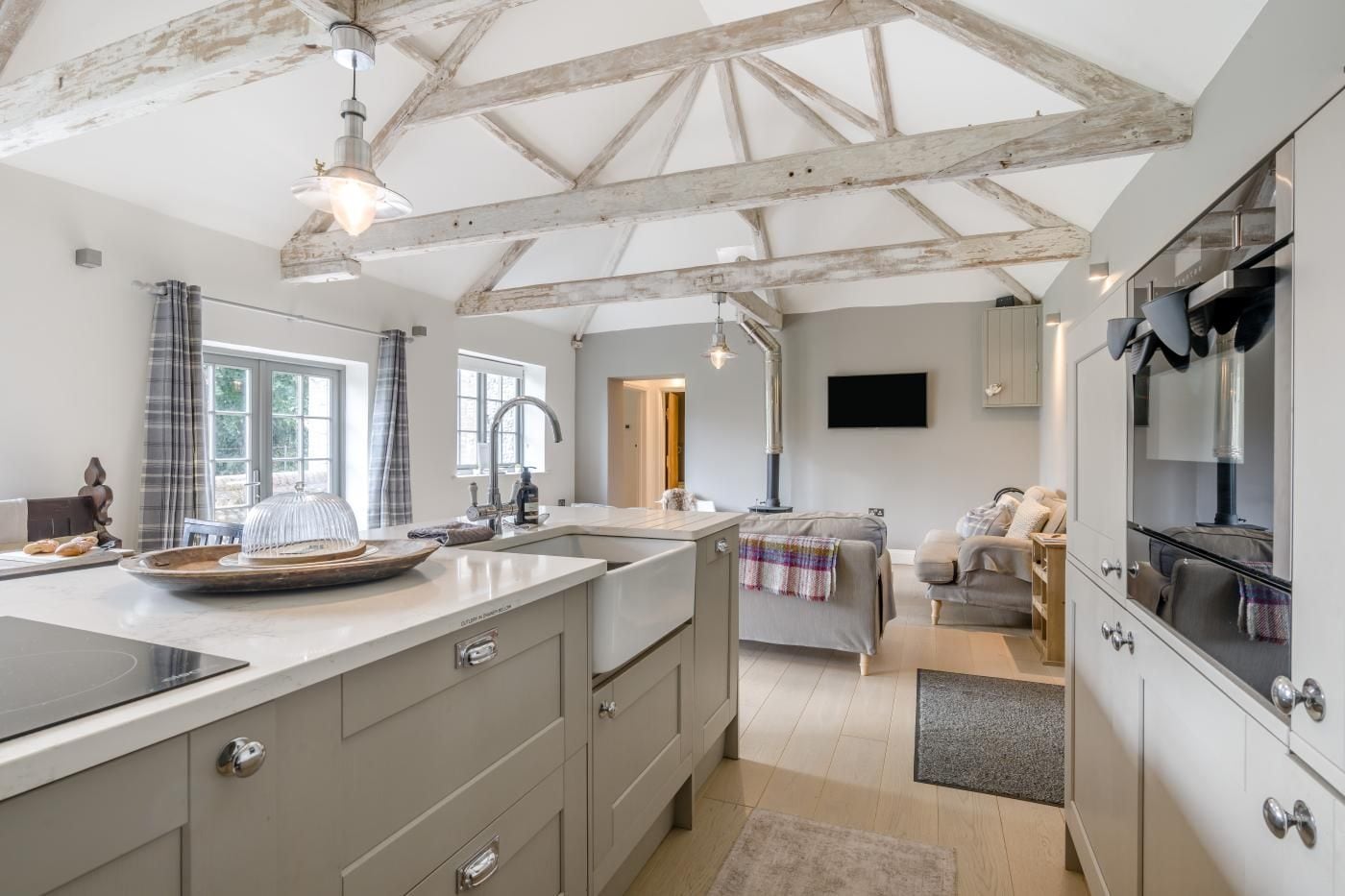 A modern kitchen with a large island, built-in appliances, and a rustic ceiling.