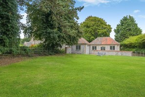 A stone building with a tiled roof, surrounded by a well-maintained lawn and trees. - 2 Bed in Northrepps (oc-c46373) (Northrepps)