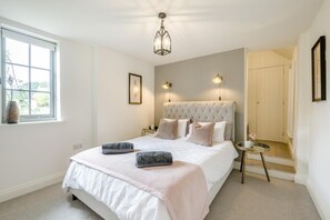 A bedroom with a large bed, a bedside table, a nightstand, a window, and a door. - 2 Bed in Northrepps (oc-c46373) (Northrepps)