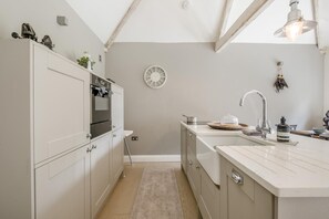 Een keuken met een inbouwoven, een spoelbak met kraan en een klok aan de muur.