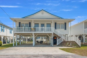 A two-story building with a balcony and a covered area with outdoor seating. - Beautiful Cherry Grove Beach House (North Myrtle Beach)