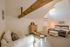 Une chambre confortable avec un lit, une table de chevet, une commode et un plafond avec une poutre en bois.
