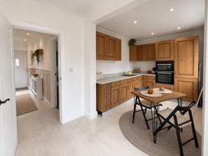 Eine moderne Küche mit Holzausstattung, einem Esstisch mit Stühlen und einem eingebauten Backofen.