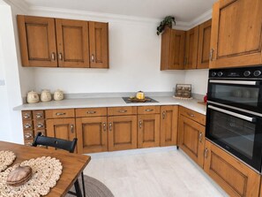 Eine Küche mit Holzausstattung, einer Arbeitsplatte, einem Spülbecken und einem Backofen.