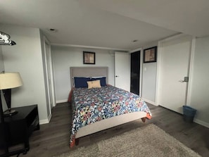 A bedroom with a bed, a nightstand, a lamp, and a door. - Cozy Lakeview Home Minutes from O'Hare (Des Plaines)