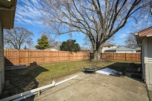 A backyard with a wooden fence, a tree, and a concrete patio. - Cozy Lakeview Home Minutes from O'Hare (Des Plaines)