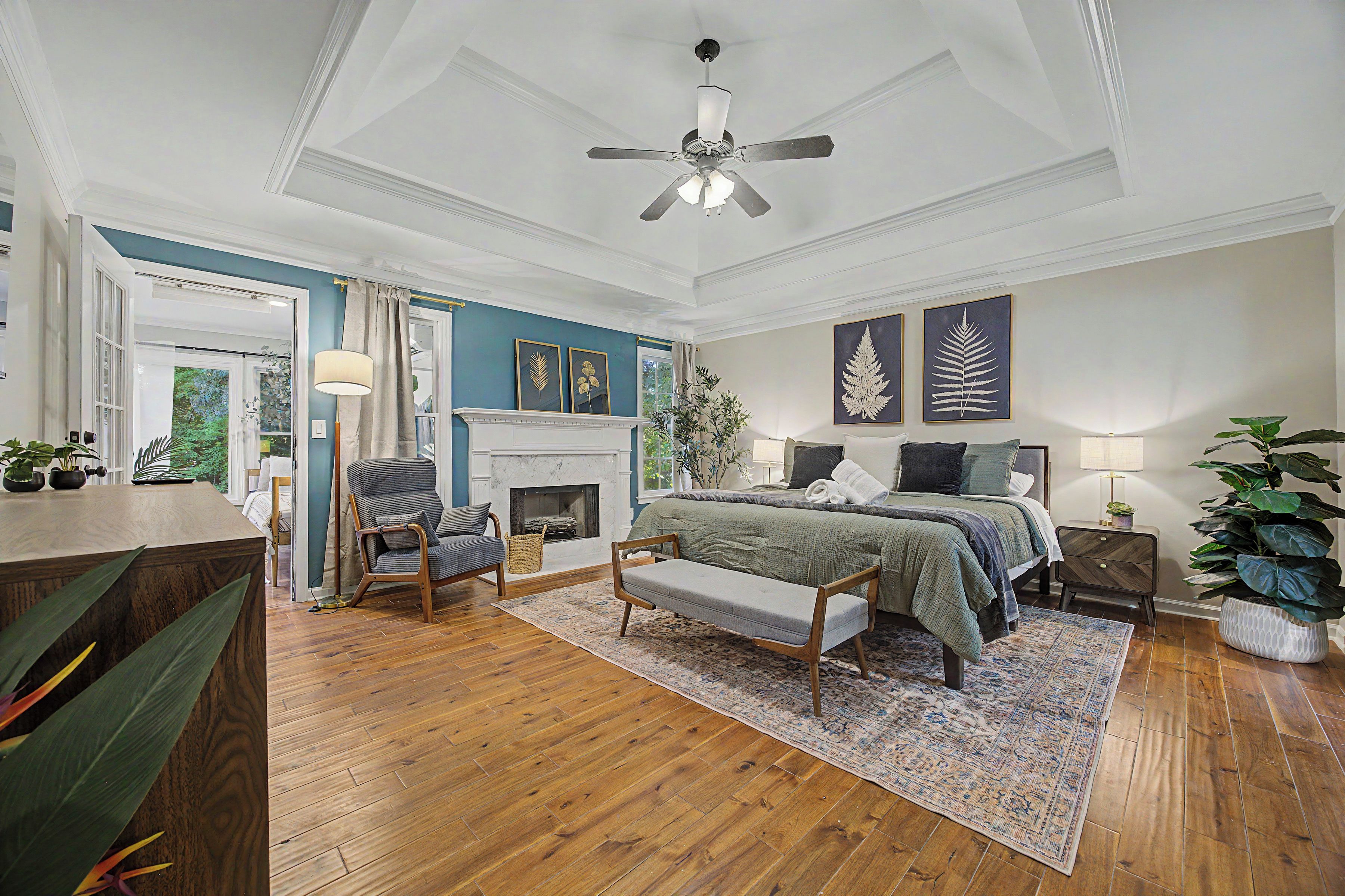 A bedroom with a bed, a chair, a fireplace, and a ceiling fan.