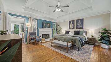 A bedroom with a bed, a chair, a fireplace, and a ceiling fan.