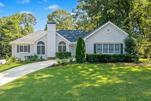 A two-story house with a front porch, a driveway, and a well-maintained lawn. - Spacious 4BR Buford Home Near Mall of Georgia (Buford)
